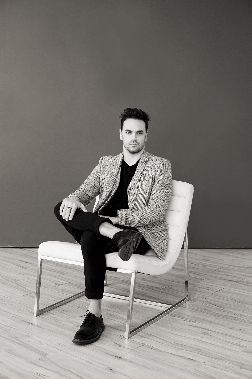 Andrew Hanson in white leather chair in black and white